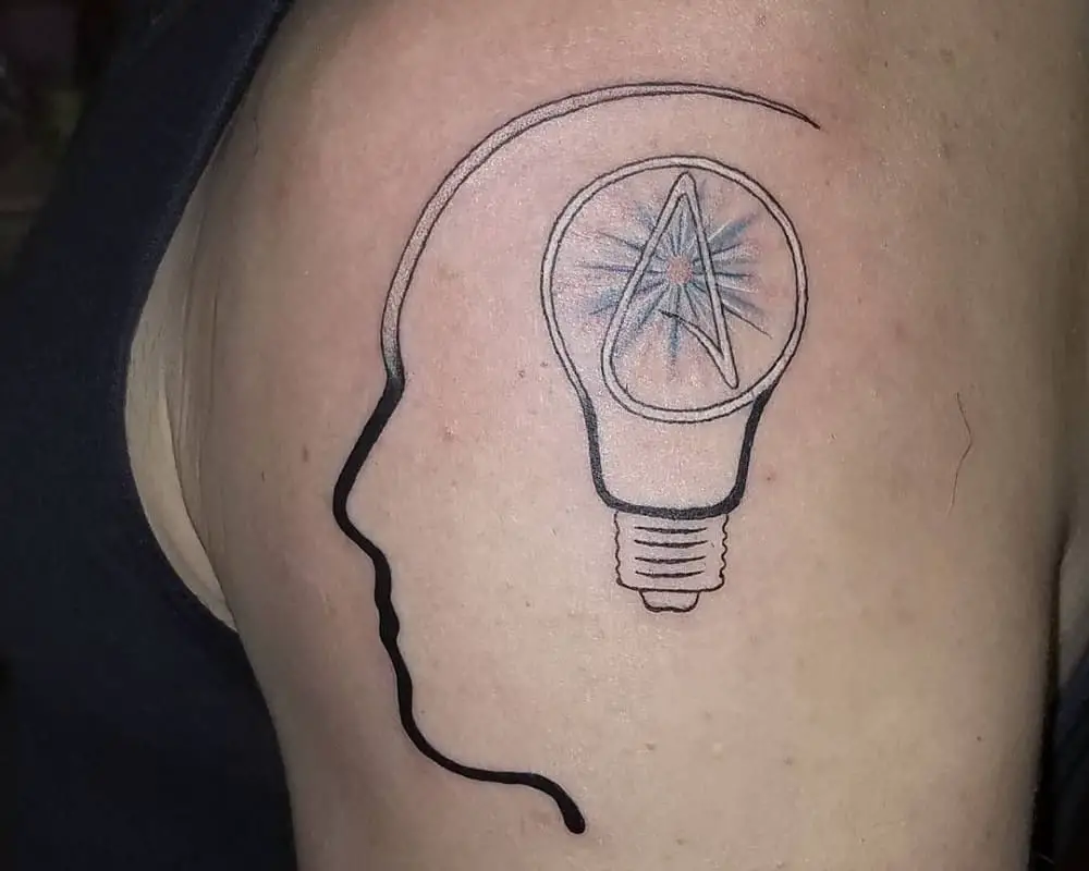 Tattoo in the shape of a human profile and a light bulb with the symbol A inside