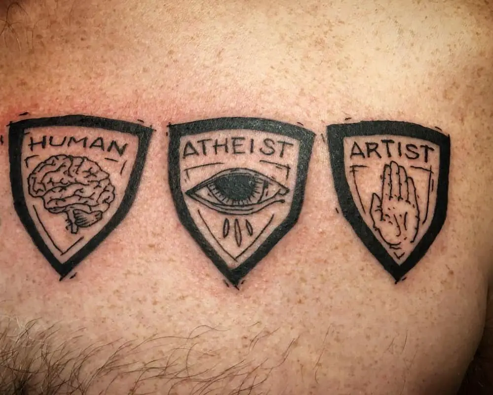 Tattoo in the shape of three shields with the inscription human atheist artist