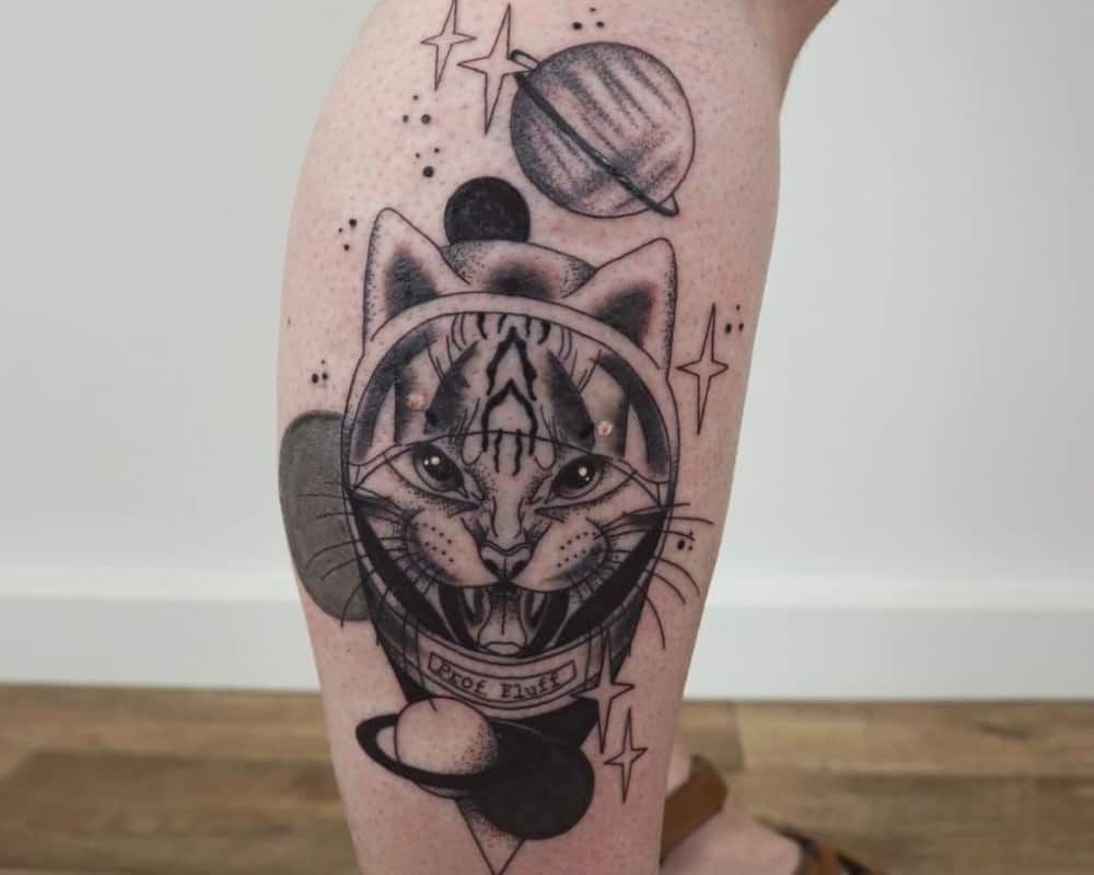 Tattoo of a cat in a spacesuit with planets in the background