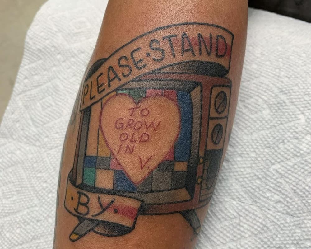 tattoo of TV with the inscription at the heart "to grow old in V." and the inscription at the top "Please stand by"