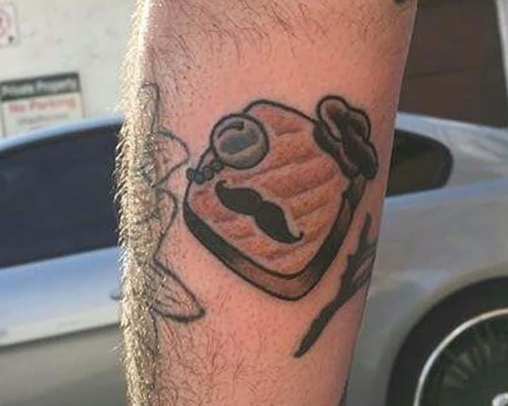 tattoo of a toast wearing a hat with a moustache and monocle
