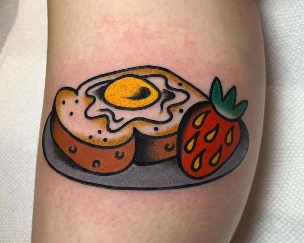 tattoo of toast with scrambled eggs and strawberries on a plate
