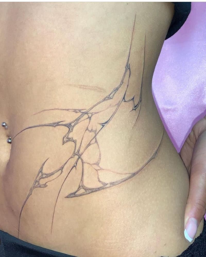 A subtle tattoo of bone wings on the waist