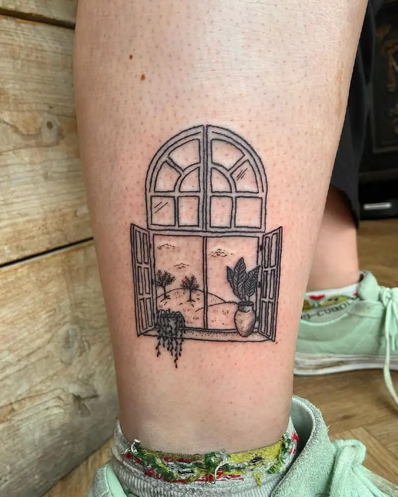 A tattoo in the form of an open window and a landscape behind it