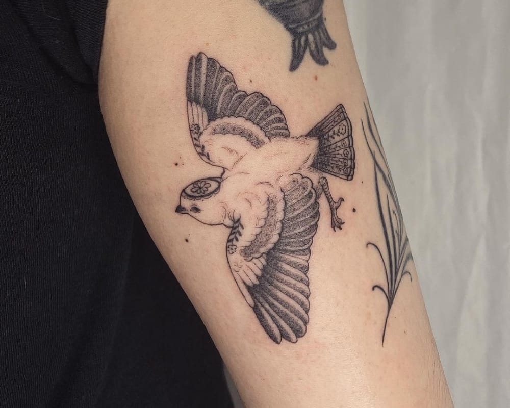 A tattoo in the shape of a bird with patterns of flowers on it