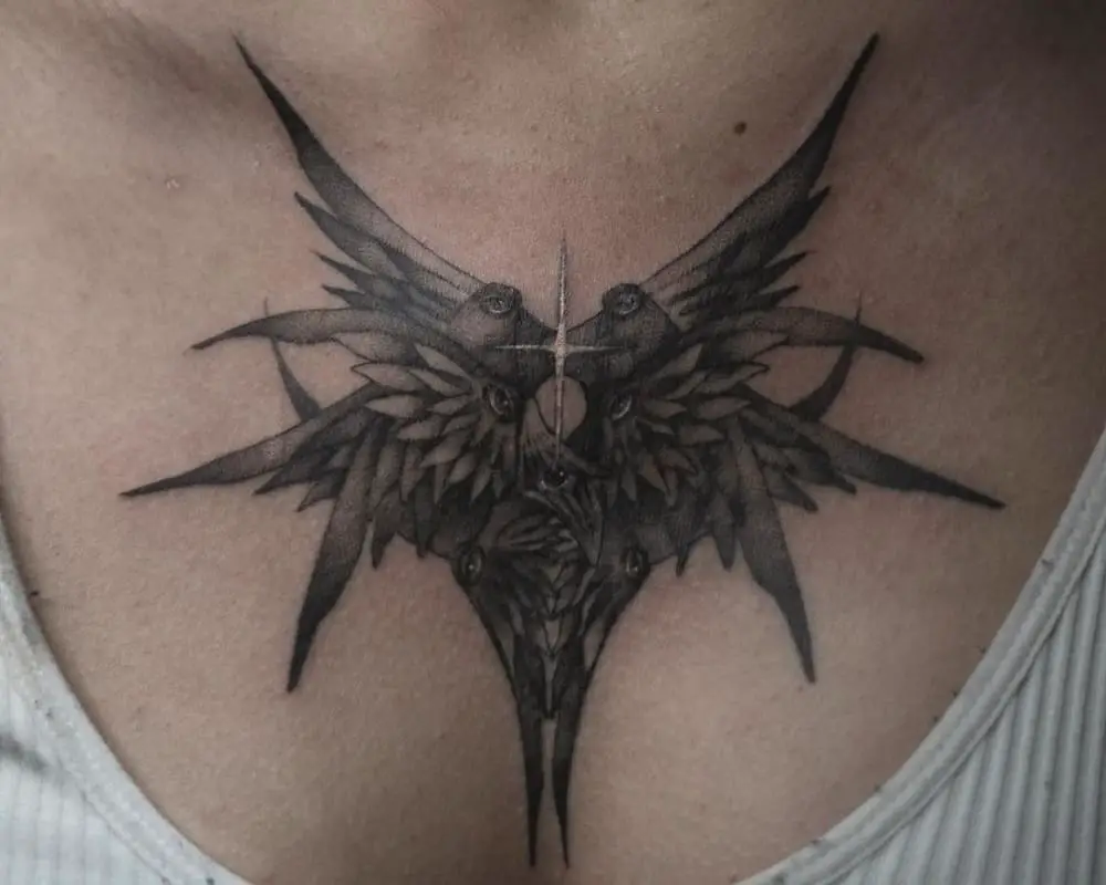 A tattoo in the shape of wings with eyes and a star in the center on the chest