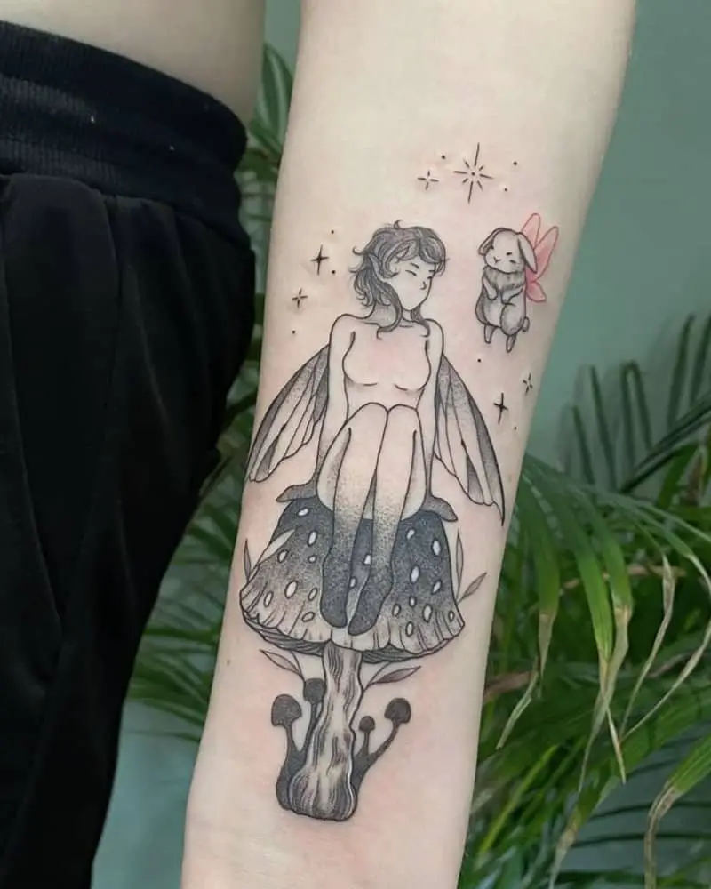 A tattoo of a beautiful fairy sitting on a mushroom with a rabbit with wings flying beside her