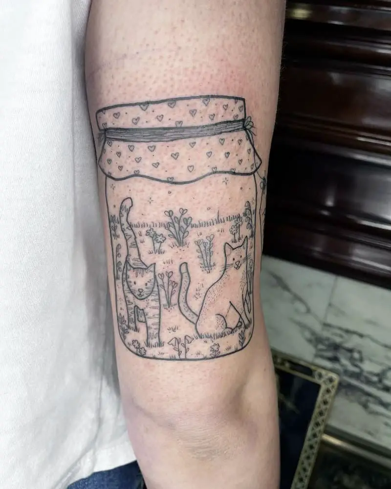 A tattoo of a jar with two cats in it