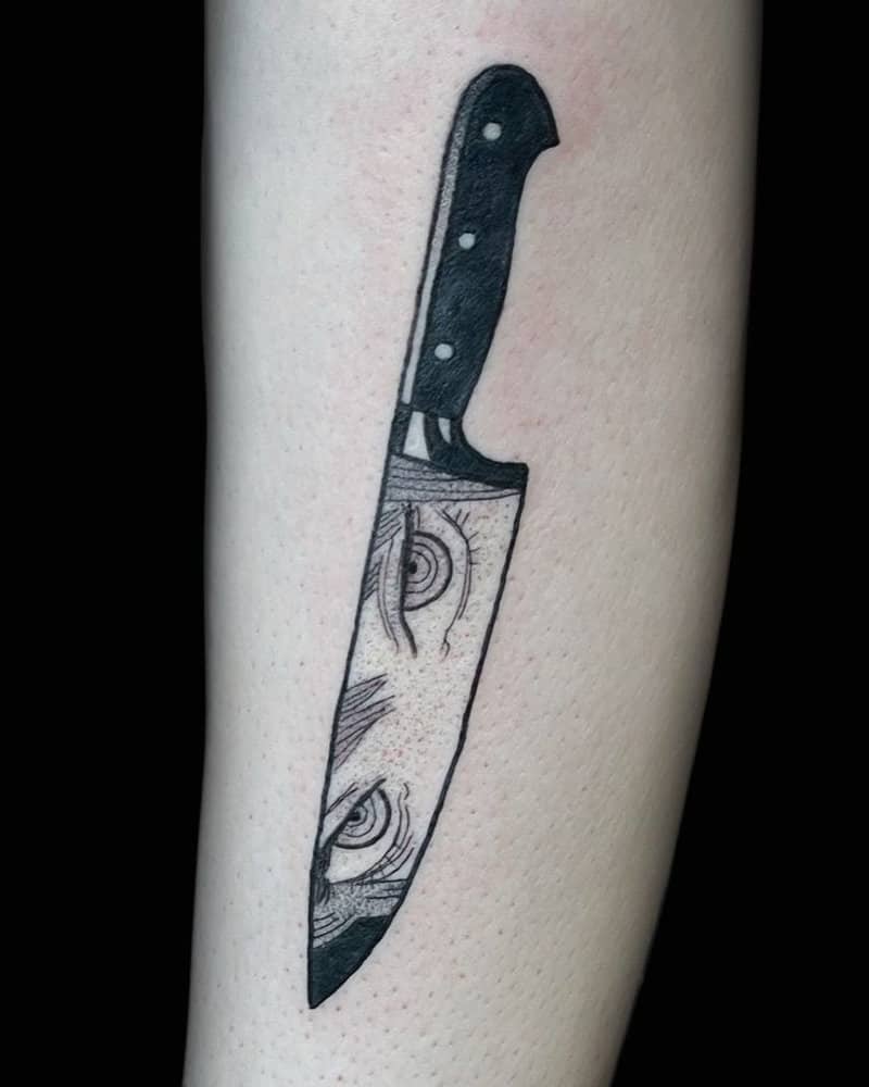 A tattoo of a knife on the blade of which you can see Makim's gaze