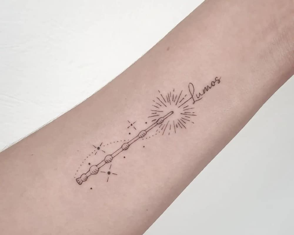 A tattoo of a magic wand and the inscription Lumos