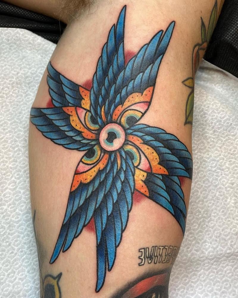 Colourful tattoo of an angel with six wings with eyes and one eye in the centre