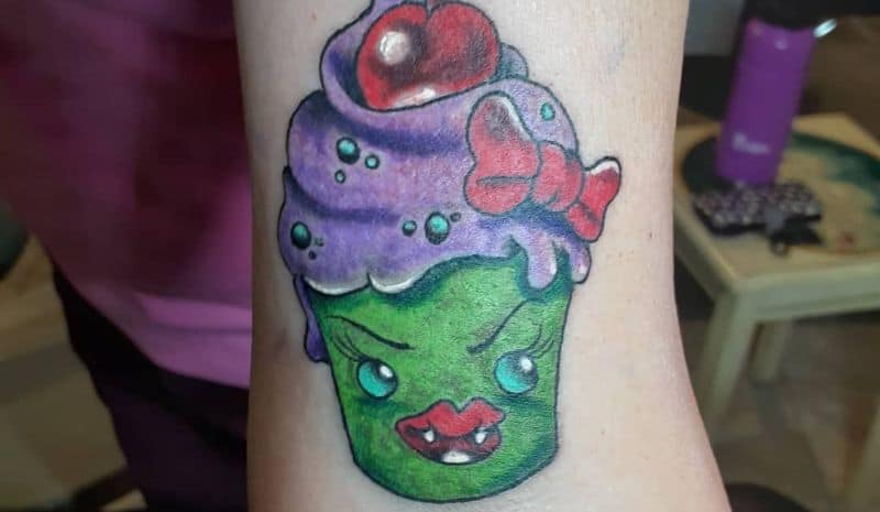 Green and purple cupcake with scary face tattoo
