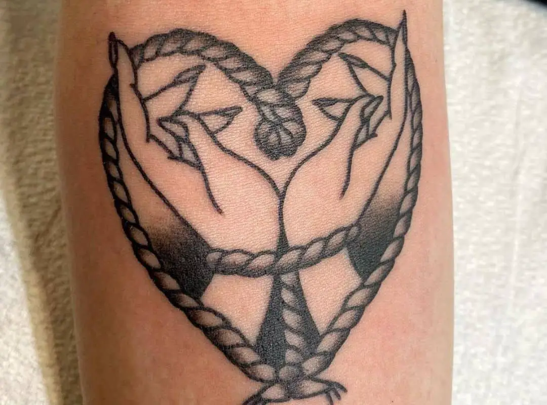 Heart-shaped ropes with arms in the middle tattoo