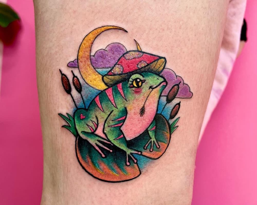 Mottled tattoo of a frog on a water lily leaf with a mushroom on its head