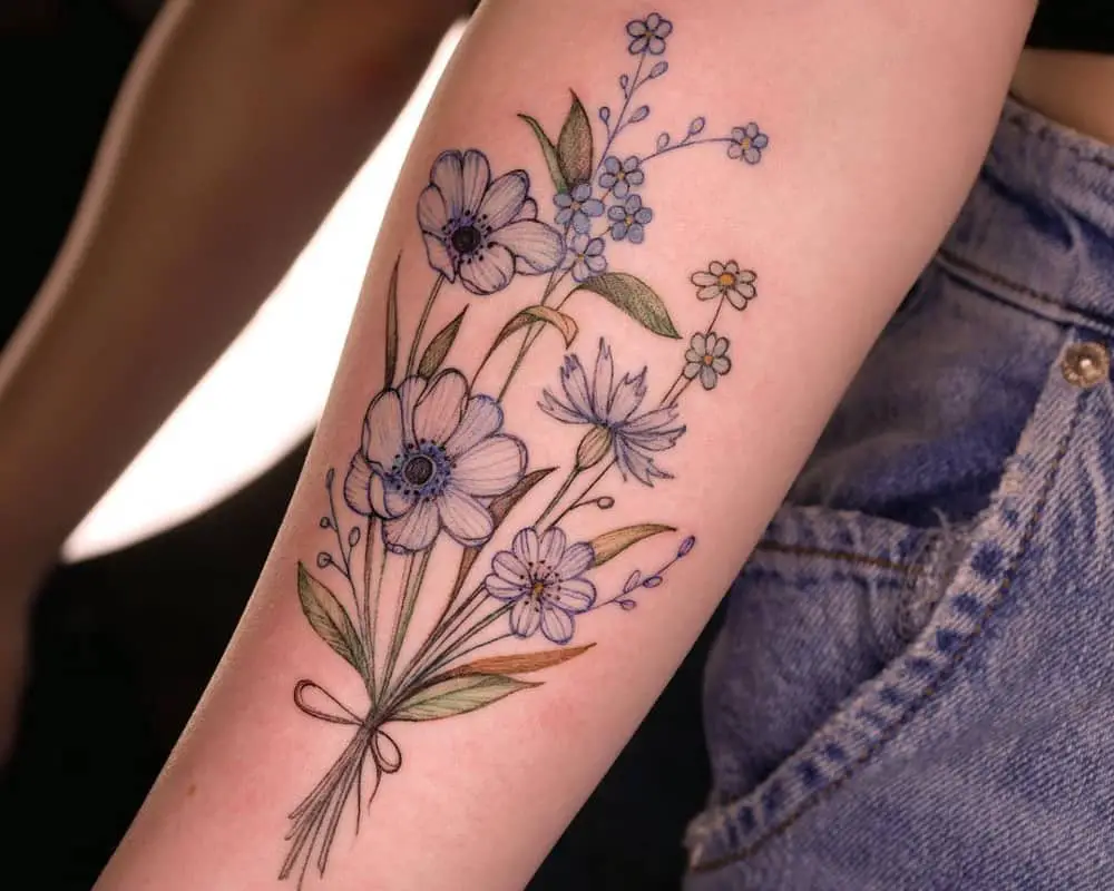 Tattoo in the form of a bouquet of blue flowers tied with a thread