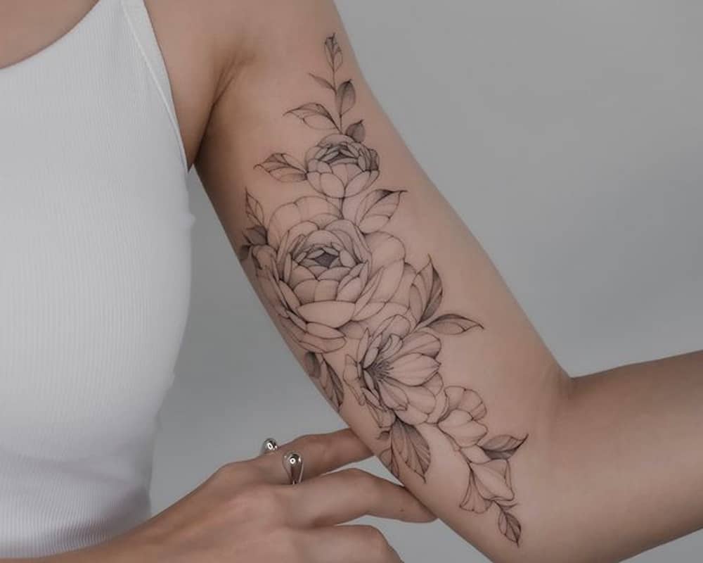 Tattoo in the form of a branch with large flowers on the hand