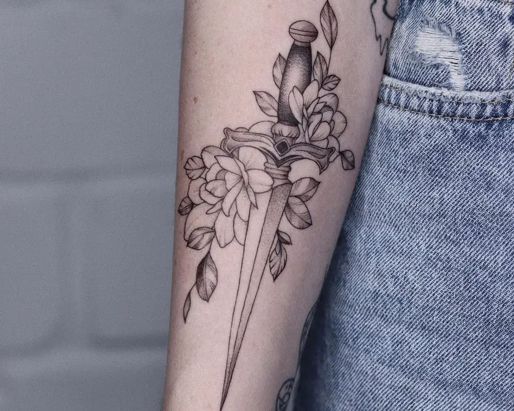 Tattoo in the form of a dagger surrounded by flowers