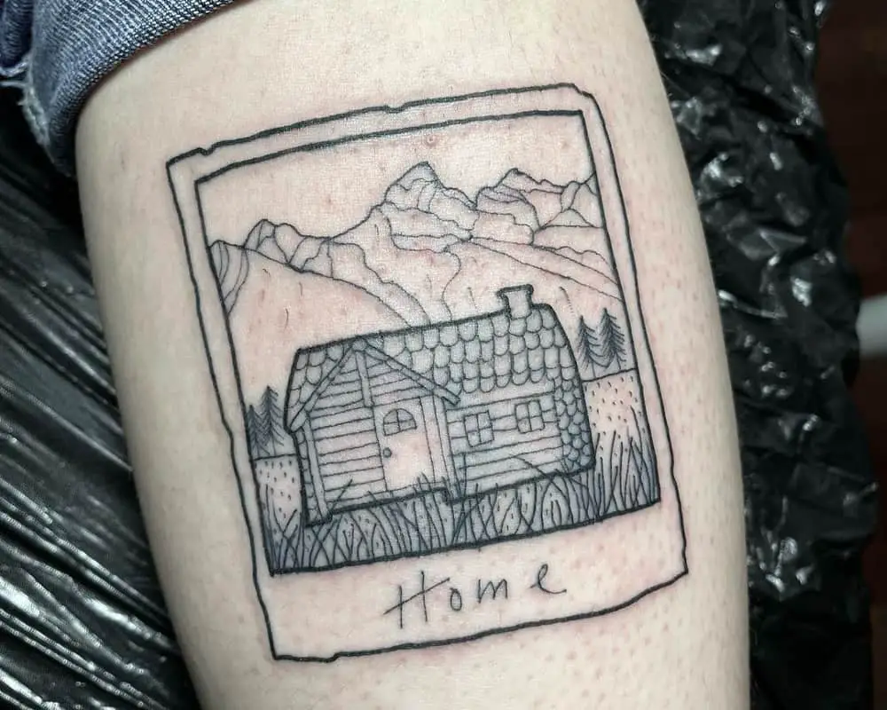 Tattoo in the form of a postcard with a small cottage and the inscription home