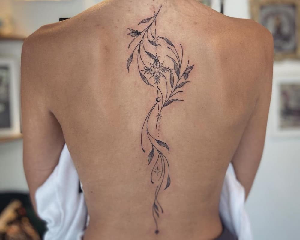 Tattoo in the form of a sprig of a plant along the spine