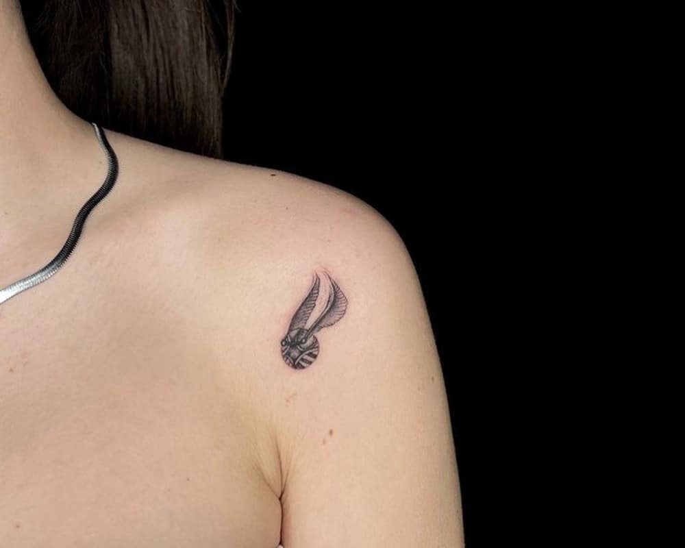 Tattoo of a golden snitch on the shoulder