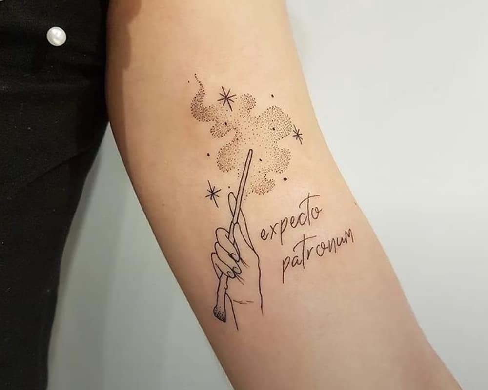 Tattoo of a hand with a magic wand and the inscription Especto Patronum