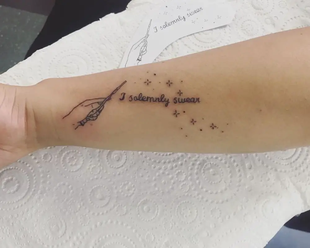 Tattoo of a hand with a magic wand and the phrase I solemnly swear