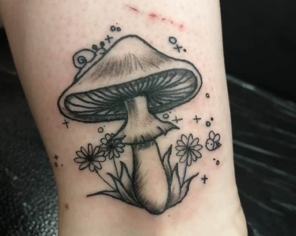 Tattoo of a small mushroom with a snail crawling on it