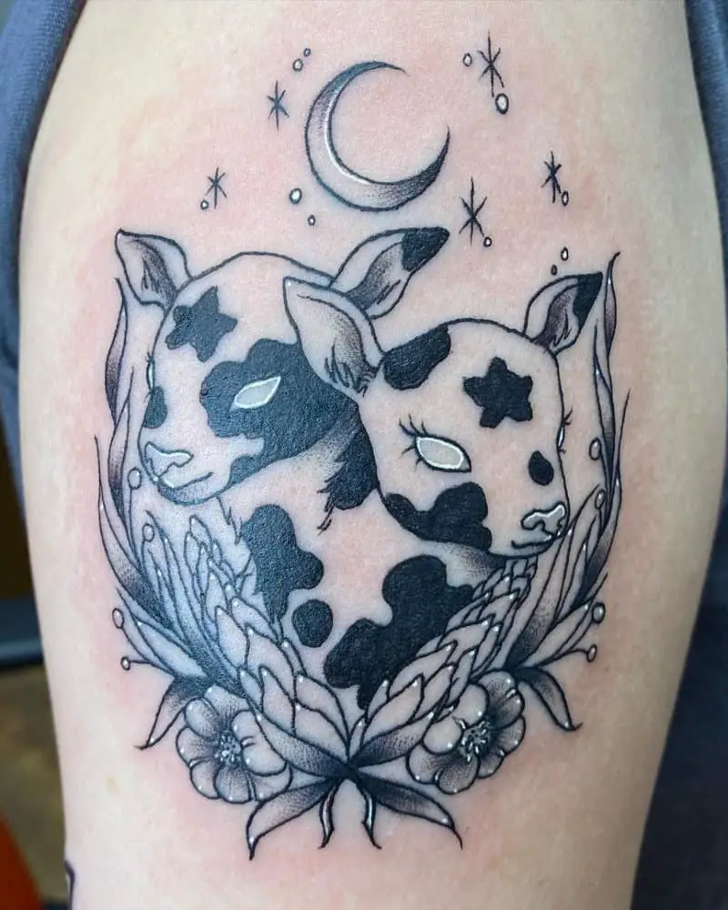 Tattoo of a spotted two-headed calf under the moon with flowers