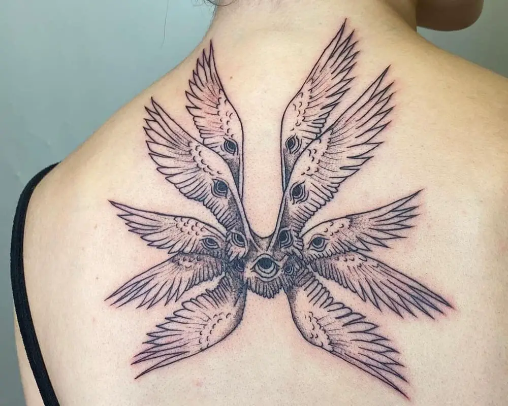 Tattoo of an angel with eight wings with eyes and one eye in the centre on the back