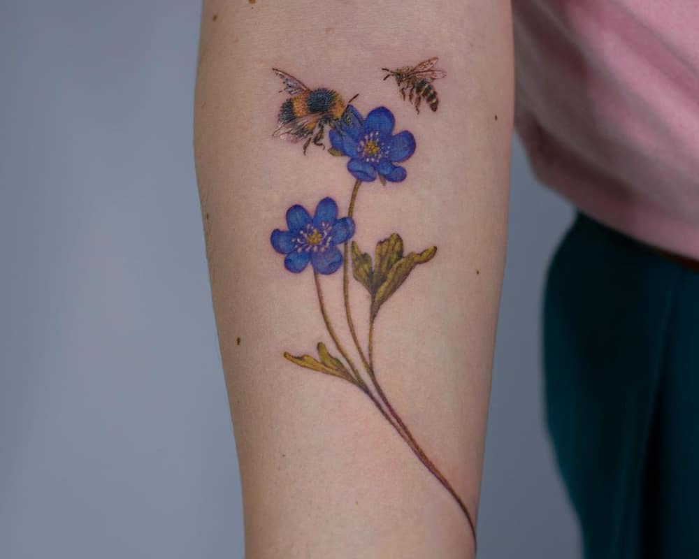 Tattoo with a branch of blue flowers and a bumblebee with a bee