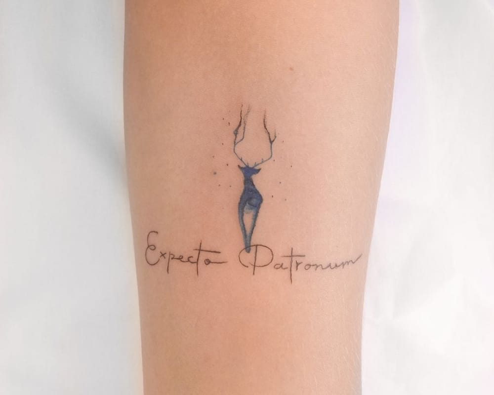 Tattoos of an exquisite blue deer and the inscription expecto Patronum