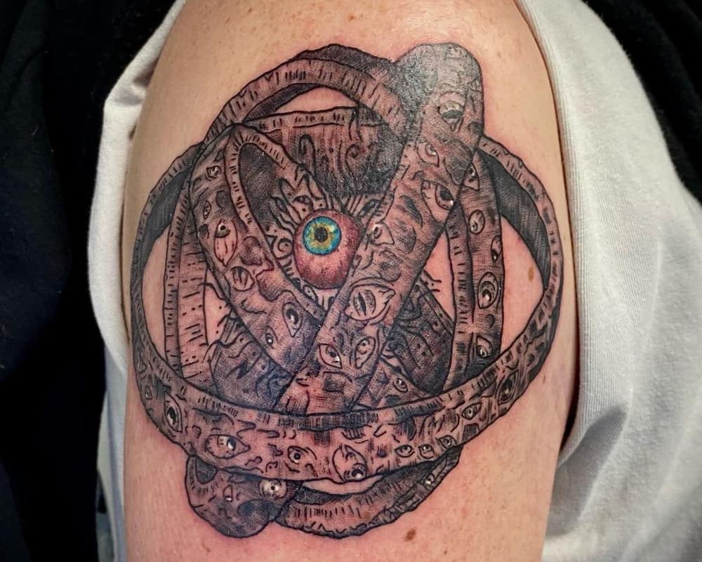Wheel tattoo with an eye and an eye in the centre on the arm