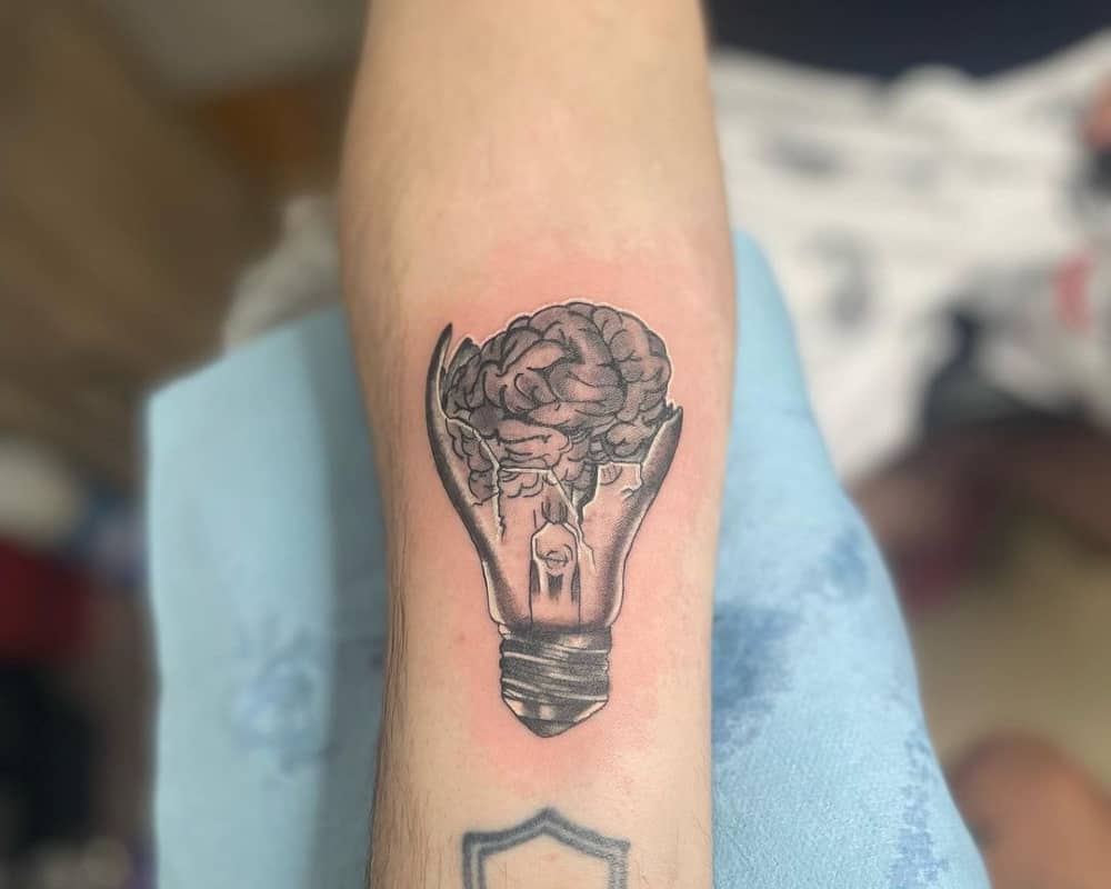 a tattoo of a broken light bulb with a brain inside