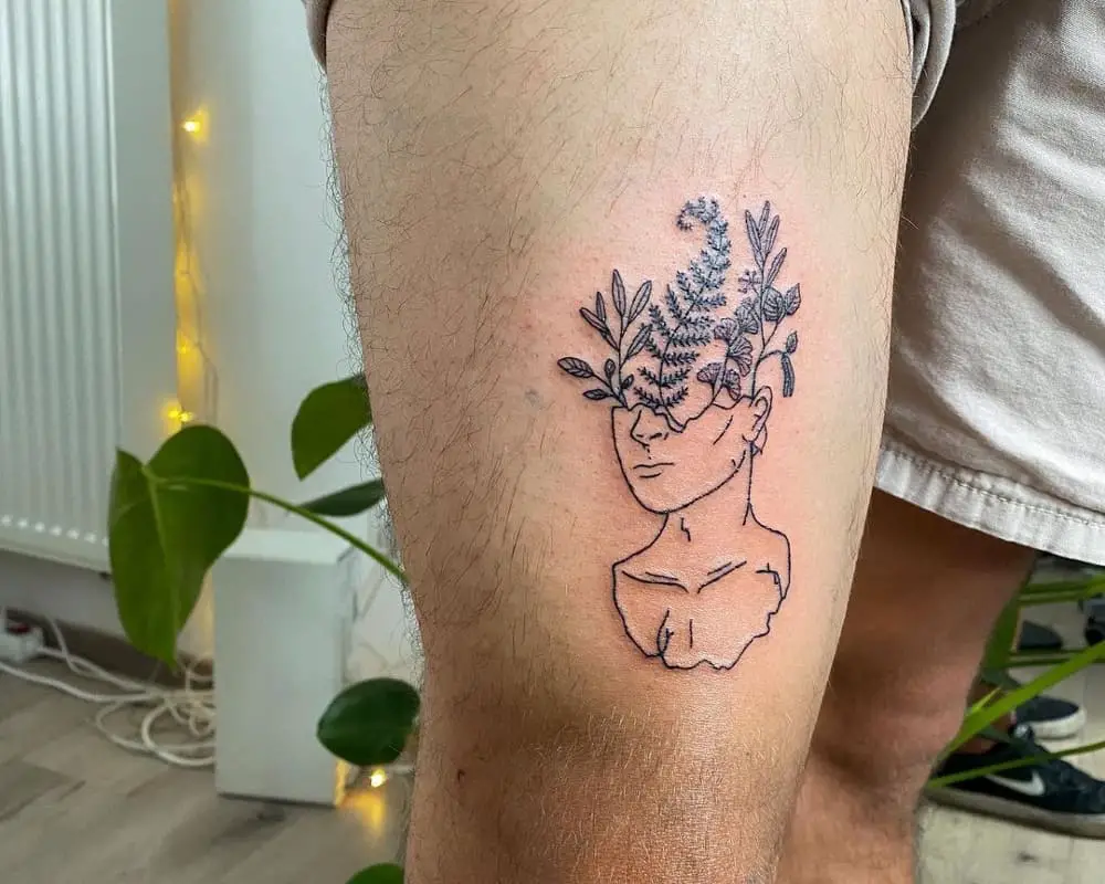 a tattoo of a head from which a plant grows