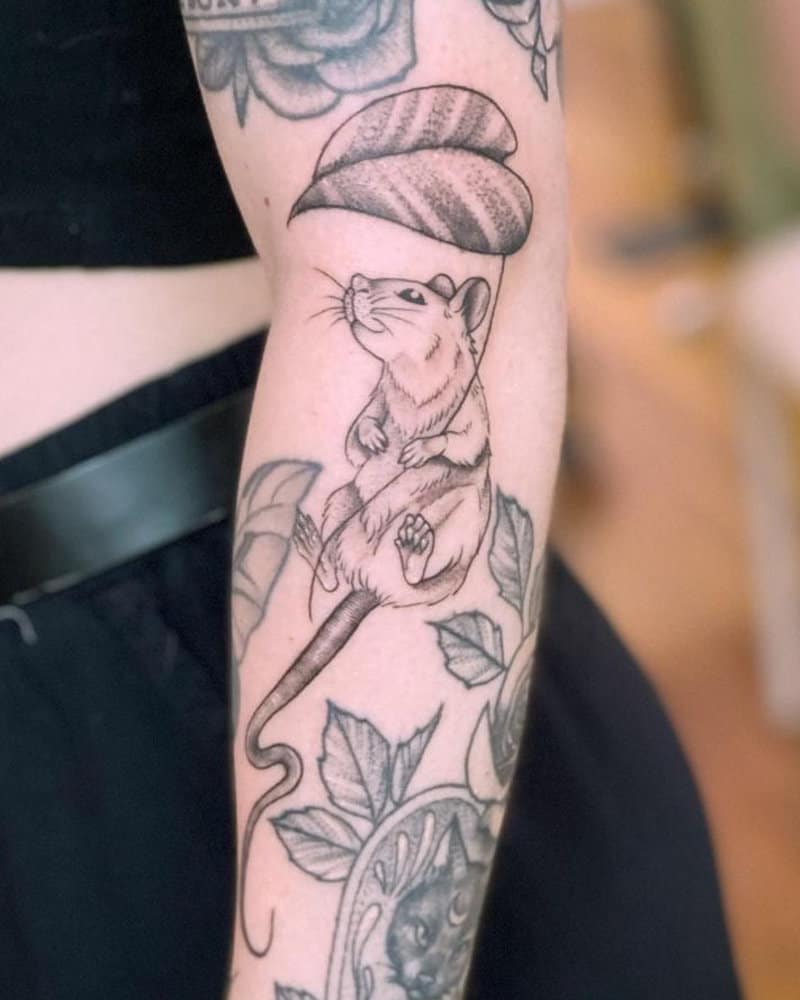 a tattoo of a mouse with a leaf in its paws