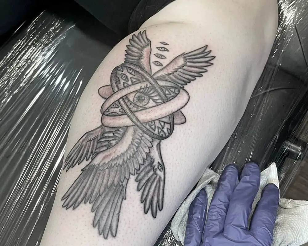 a tattoo of wheels with eyes inside and three pairs of wings