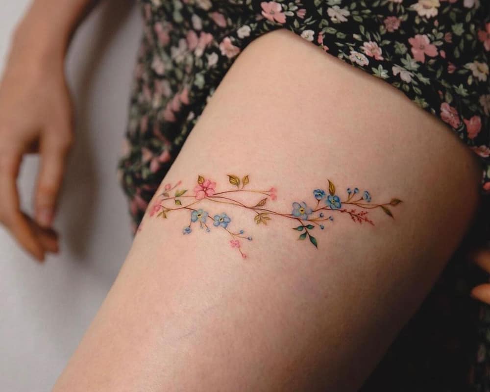 a very delicate tattoo of a branch of colored flowers