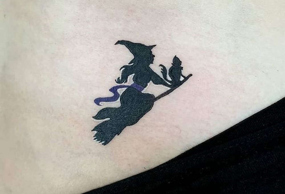 small tattoo of a witch with a cat flying on a broomstick