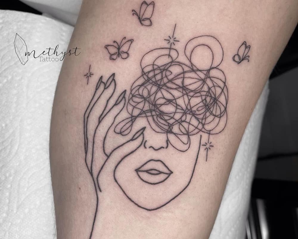 tattoo in the form of a silhouette of a woman's head with intricate lines in it