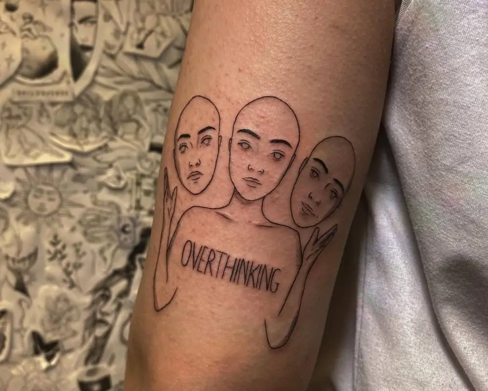 tattoo in the form of a silhouette with three faces and the inscription overthinking