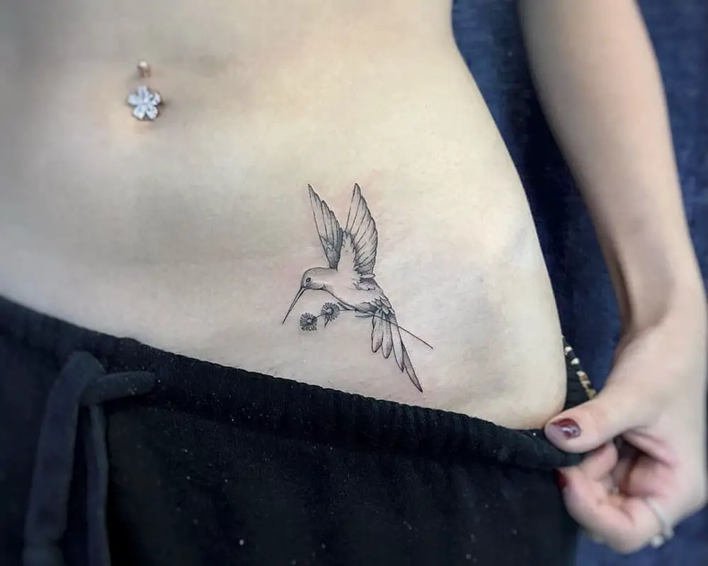 tattoo of a bird caliber with a flower in its paws