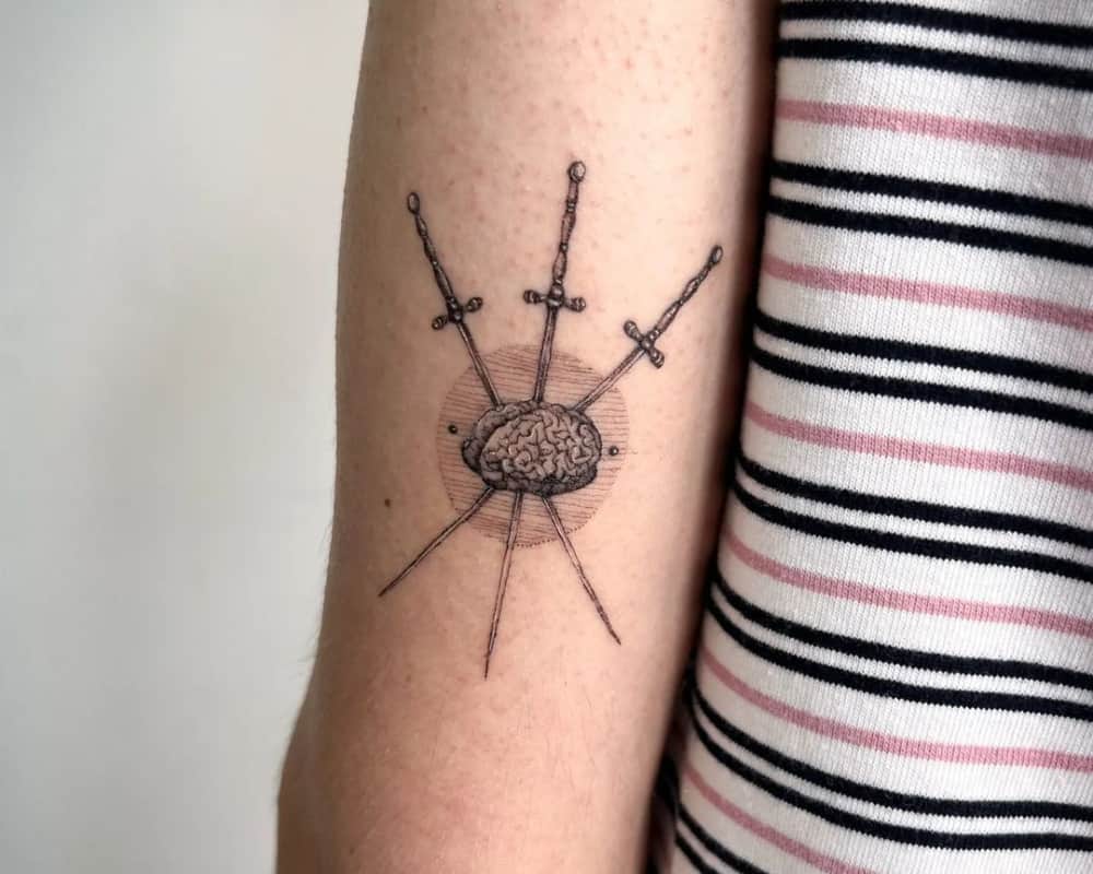 tattoo of a brain pierced by three swords