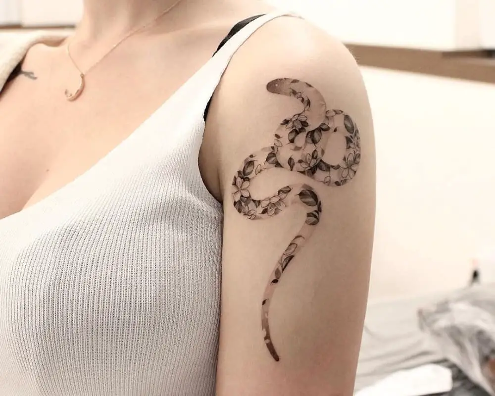 tattoo of a flowery silhouette of a snake on the shoulder