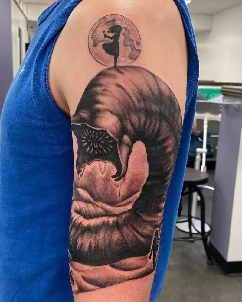 tattoo of a girl standing on a sand worm against the background of the moon