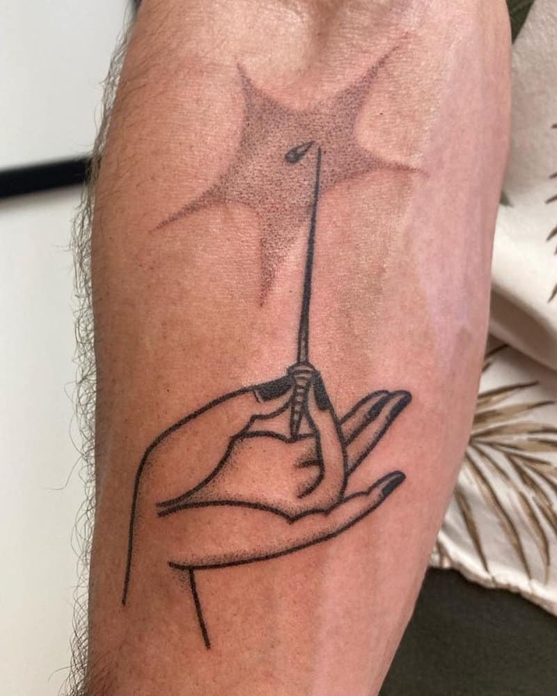 tattoo of a hand holding a needle
