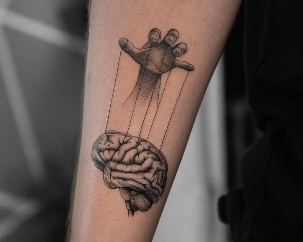 tattoo of a hand manipulating the brain