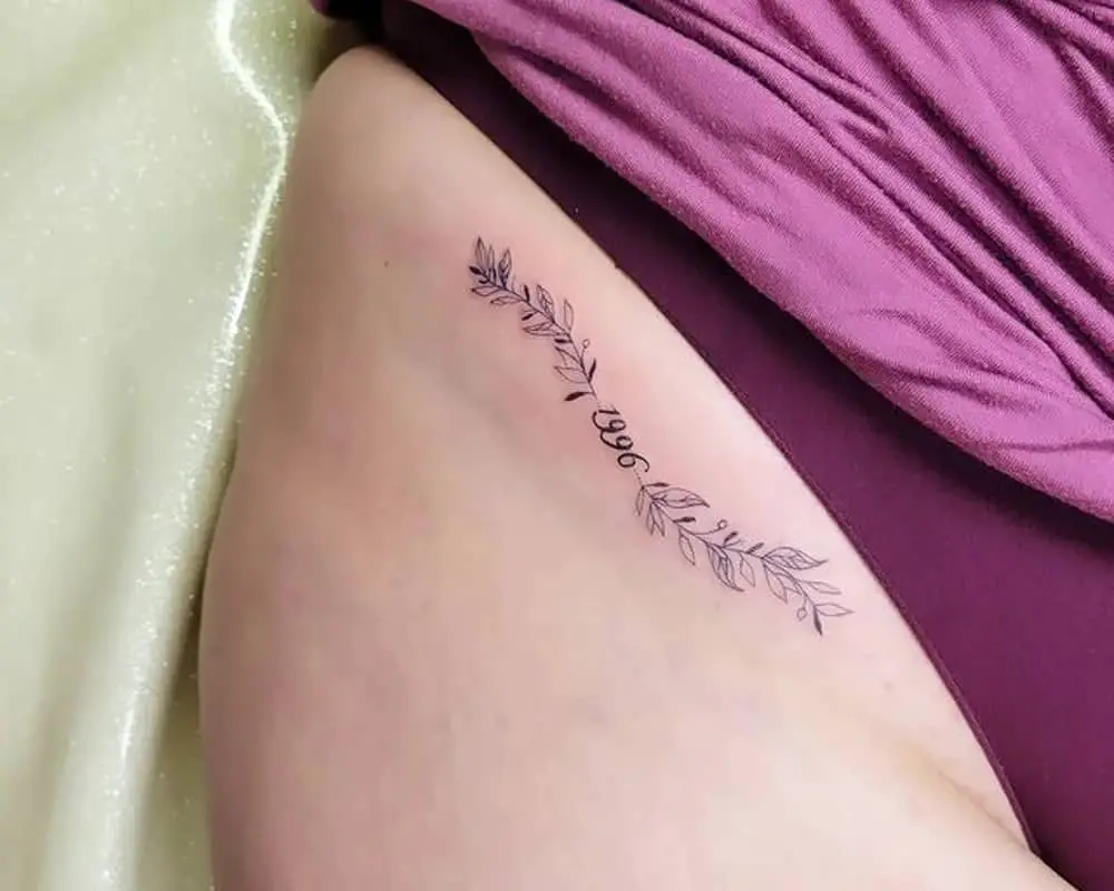 tattoo of a twig with leaves and the date 1996