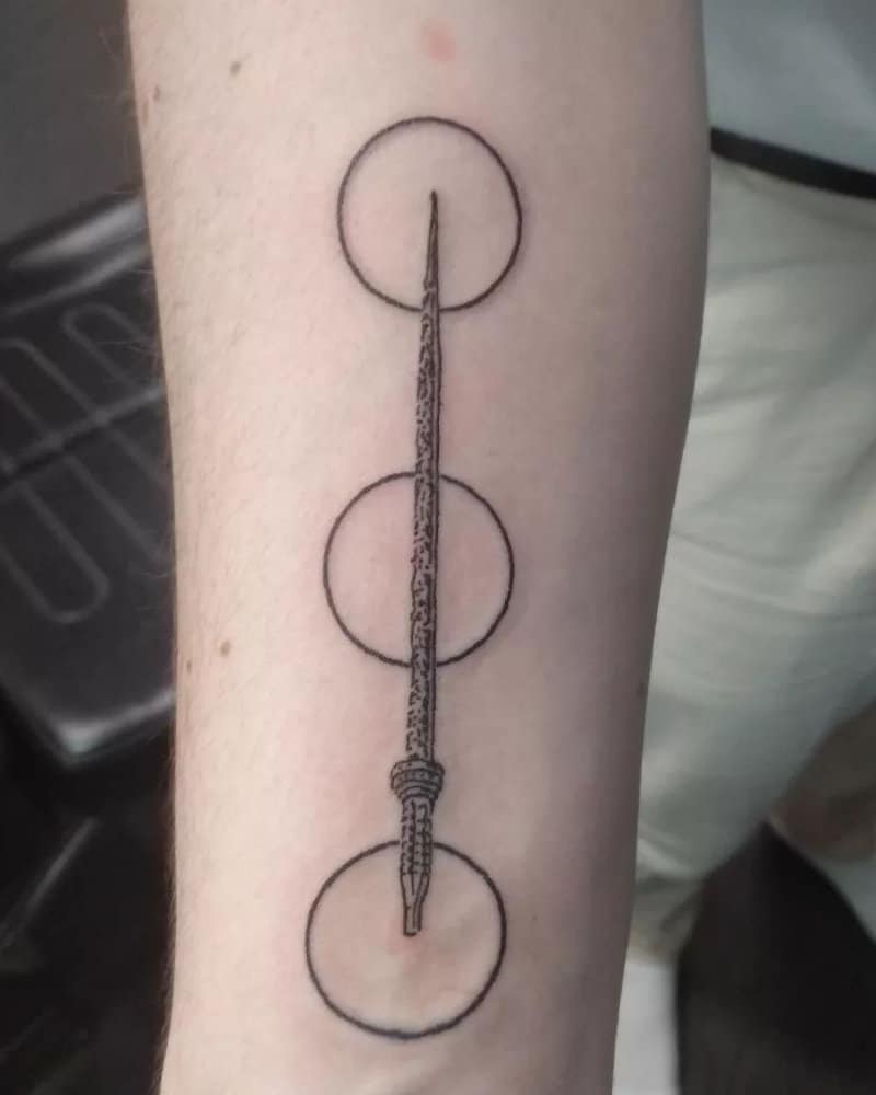 tattoo of three circles connected by a sword