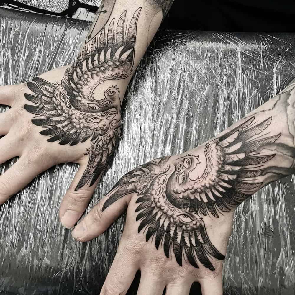 unusual tattoo of an angel with six crane wings with eyes on two hands