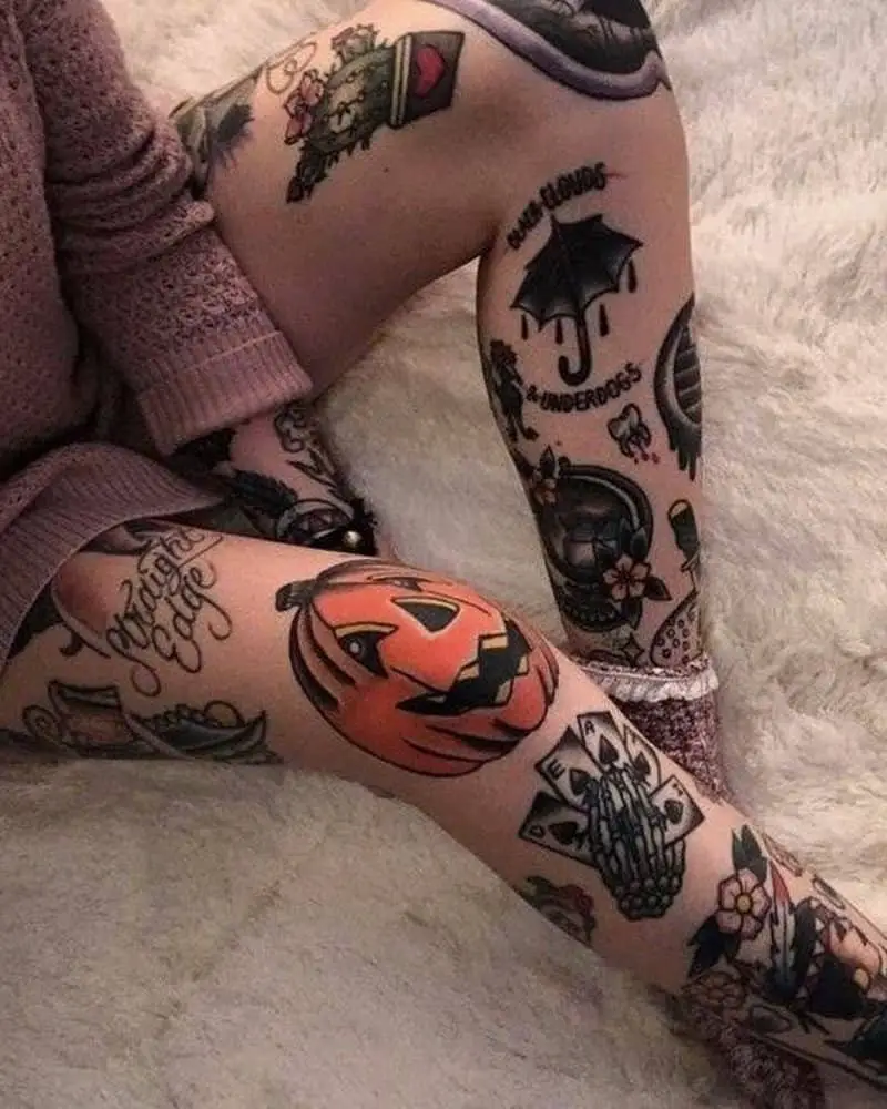 women's legs with lots of tattoos, such as Halloween pumpkin, cards in a bone hand, cactus, umbrella and others